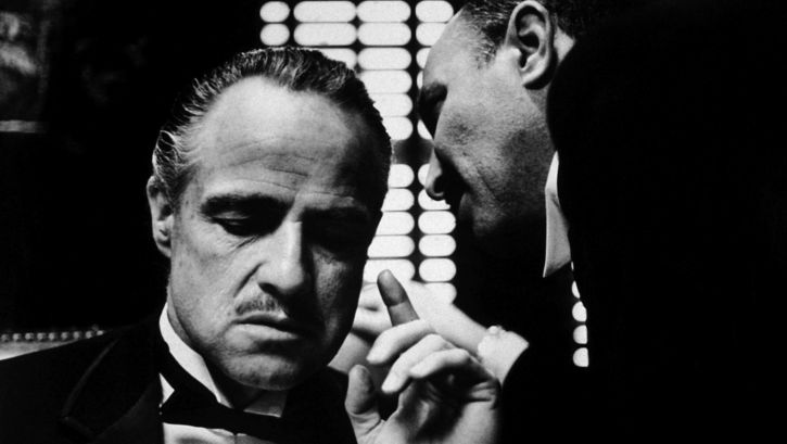 Film still from THE GODFATHER: A man whispers something in another man