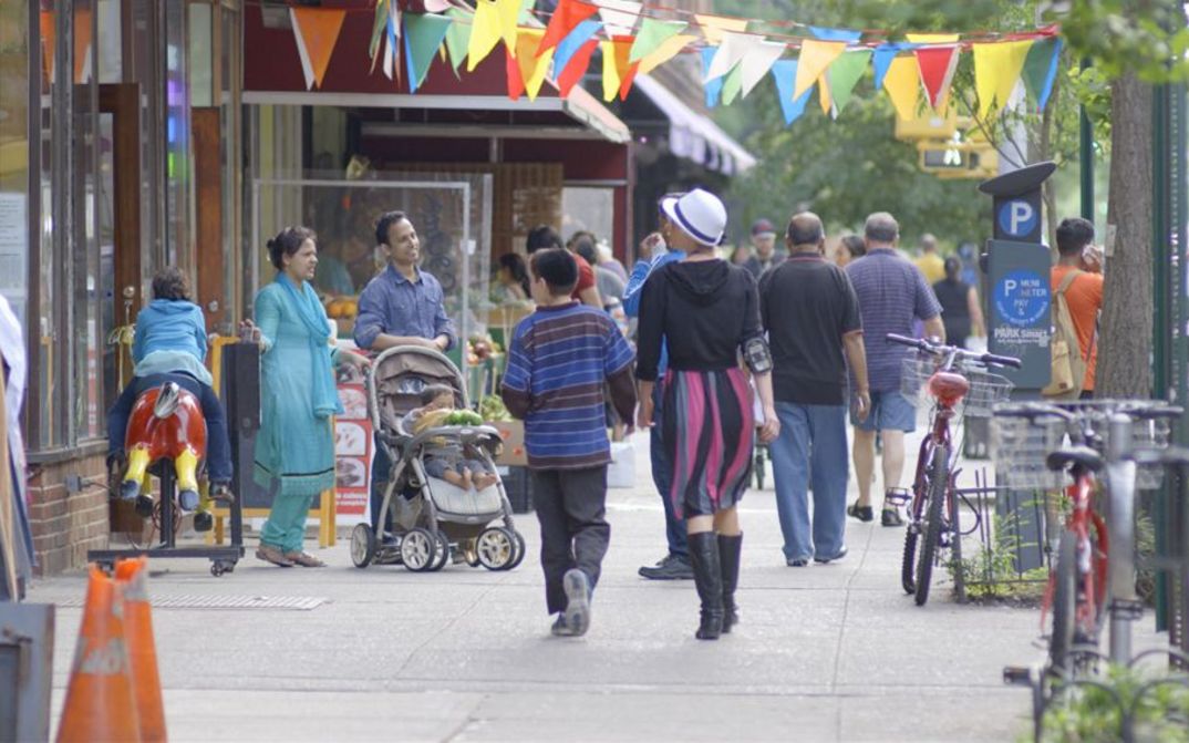 Filmstill aus IN JACKSON HEIGHTS. Menschen auf der Straße im New Yorker Stadtteil Jackson Heights.