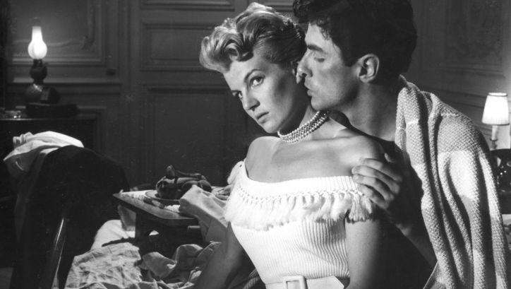 Filmstill aus LE RAGAZZE DI SAN FREDIANO: Ein Mann und eine Frau sitzen angezogen am Bettrand. Er sitzt hinter ihr und küsst sie auf den Hals.