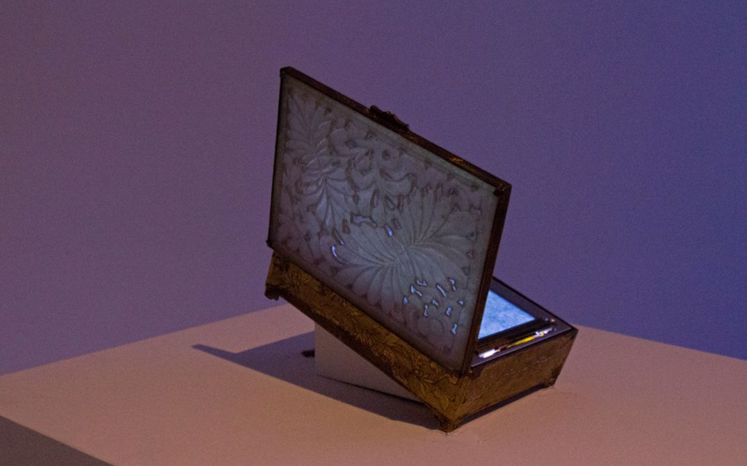 Installation view of Tenzin Phuntsog’s „Summer Grass“. An opened box on a pedestal with a screen inside.