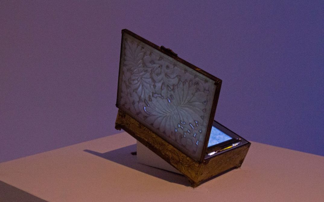 Installation view of Tenzin Phuntsog’s „Summer Grass“. An opened box on a pedestal with a screen inside.