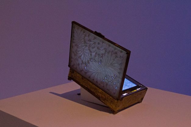Installationsansicht zum Werk „Summer Grass“ von Tenzin Phuntsog. Eine geöffnete Box auf einem Sockel mit einem Bildschirm darin.