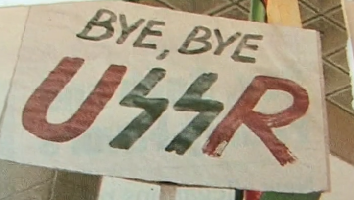 Filmstill aus LITHUANIA AND THE COLLAPSE OF THE USSR. Ein Plakat mit dem Schriftzug "Bye, bye USSR".