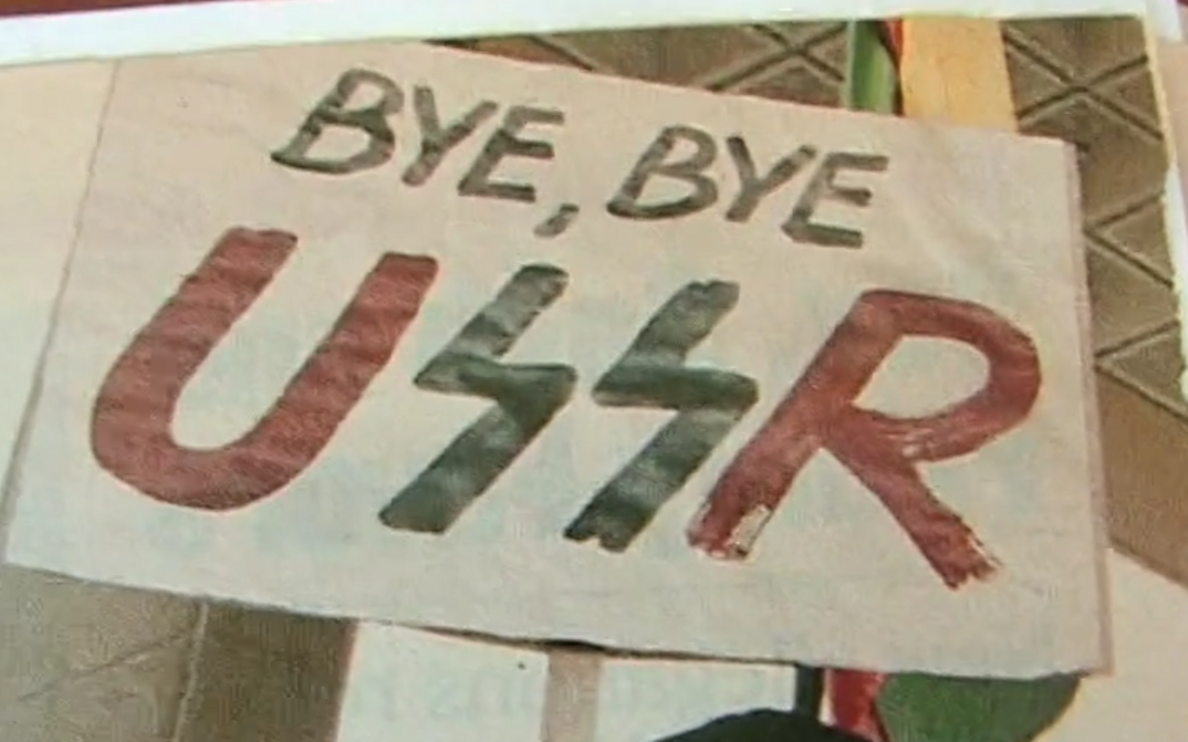 Film still from LITHUANIA AND THE COLLAPSE OF THE USSR. A poster with the words "Bye, bye USSR".