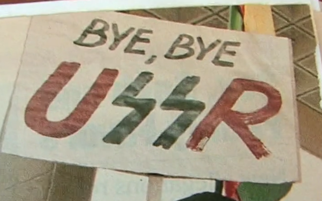 Film still from LITHUANIA AND THE COLLAPSE OF THE USSR. A poster with the words "Bye, bye USSR".