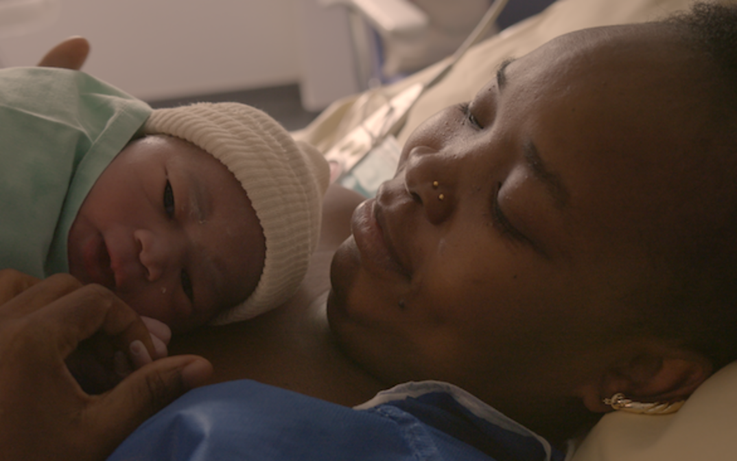 Filmstill aus NOTRE CORPS: Eine Mutter mit ihrem neugeborenen Baby im Krankenhausbett.