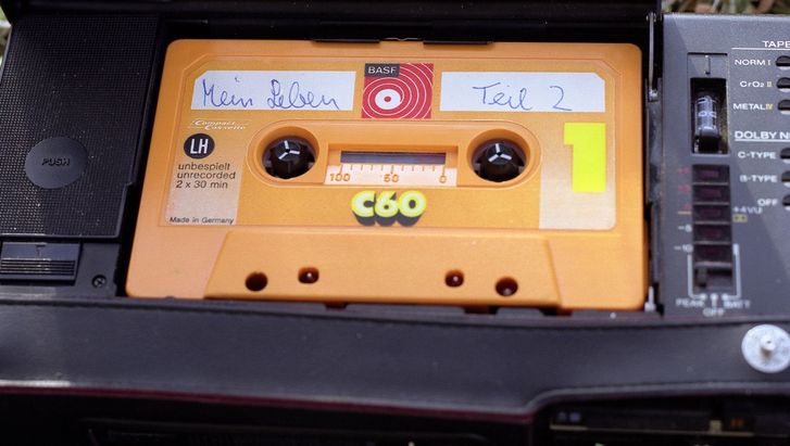 Still aus MEIN LEBEN TEIL 2: Eine gelbe Audiokassette ist handschriftlich mit dem Titel "Mein Leben Teil 2" versehen.
