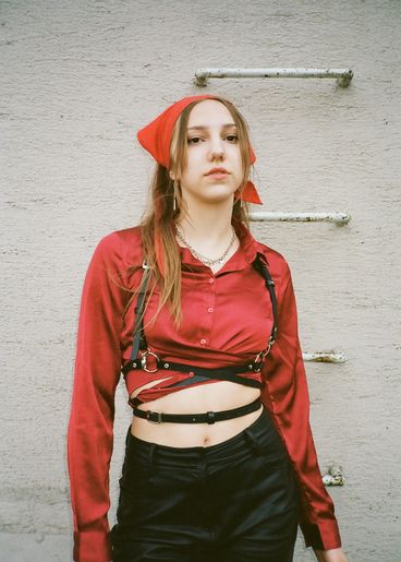 Teenager with red scarf on head looks challengingly at camera