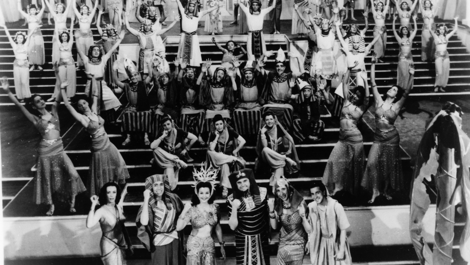 Filmstill aus LA CORTE DE FARAÓN: Eine Musical-Choreographie auf einer Showtreppe, die Darsteller in ägyptischen Kostümen.