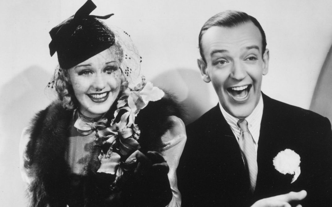 Film still from SWING TIME. Ginger Rogers and Fred Astaire laugh at the camera.
