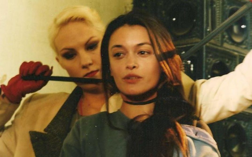 Film still from THREE STORIES: One woman stands behind another and strangles her with a stocking.