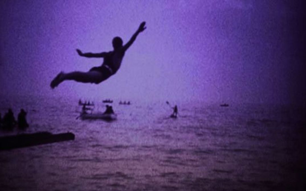 Filmstill aus LA BOCCA DEL LUPO: Monochrom eingefärbtes Bild eines Mannes, der ins Meer springt.
