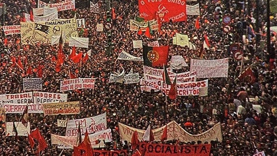 Film still from AS ARMAS E O POVO: You can see the crowd at a huge demonstration. Many have large banners or flags with them.