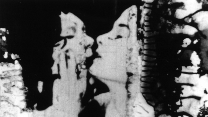 Filmstill aus THE COLOR OF LOVE: Ein sich küssendes Paar. An den Rändern zersetzt sich der Filmstreifen.