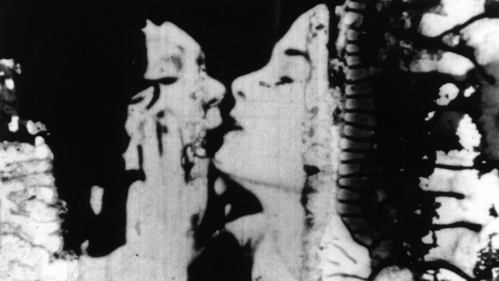 Film still from THE COLOR OF LOVE: A couple kissing. At the edges the film strip is decomposing.