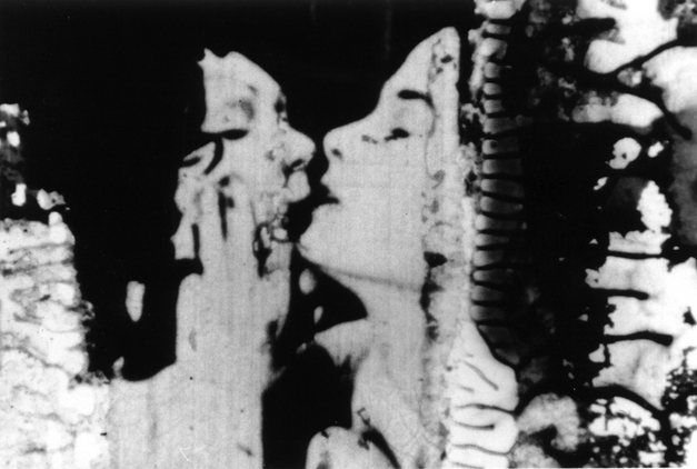 Filmstill aus THE COLOR OF LOVE: Ein sich küssendes Paar. An den Rändern zersetzt sich der Filmstreifen.