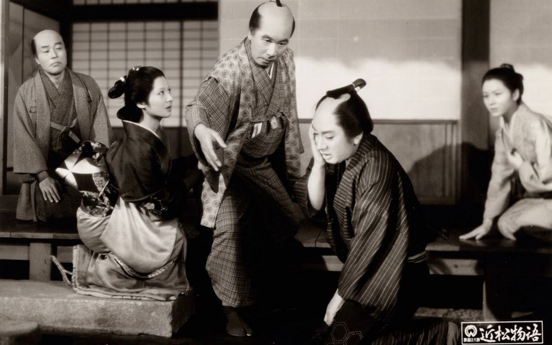 Filmstill aus dem japanischen Film CHIKAMATSU MONOGATARI. Drei Männer und zwei Frauen in historischen Kimonos, ein Mann ohrfeigt einen anderen.