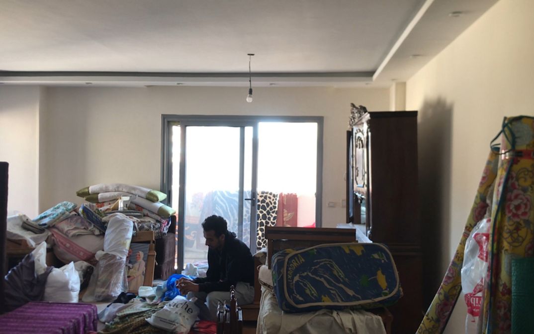 Film still from Mahmoud Ibrahim film’s “Akher Youm”. In a living room cluttered with boxes and furniture awaiting removal, a man sits amidst the impending chaos.