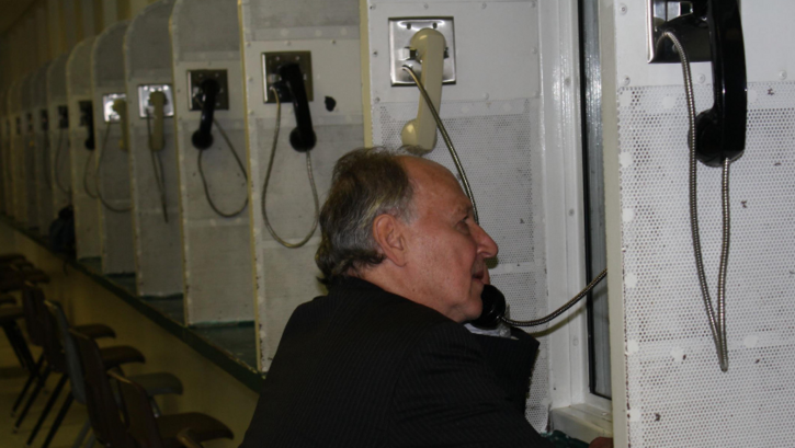 Film still from ON DEATH ROW (Part II): Werner Herzog on the phone in a prison.