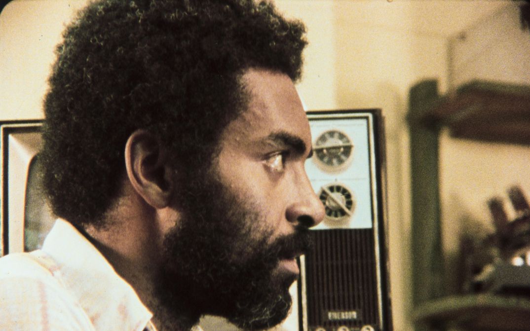 Film still from ASHES AND EMBERS: The profile of a man, in the background there is a TV.