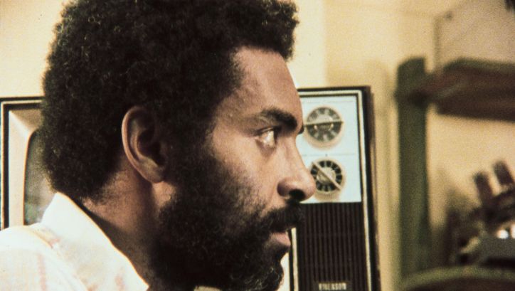 Film still from ASHES AND EMBERS: The profile of a man, in the background there is a TV.