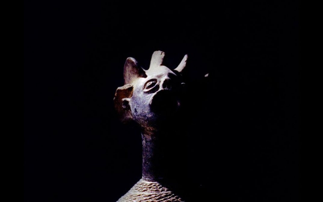 Still from the film "Under the White Mask: The Film That Haesaerts Could Have Made" von Matthias De Groof. A wooden mask is shown against a black background.