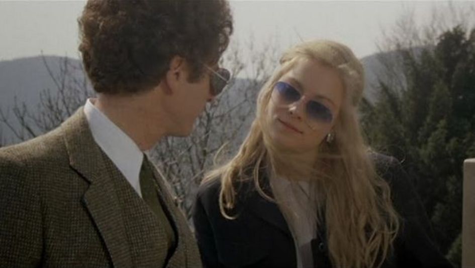 Film still from BAD TIMING: A woman and a man are standing outside, looking at each other. They're both wearing sunglasses.