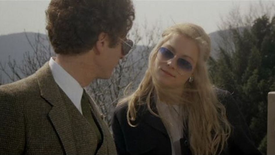 Filmstill aus BAD TIMING: Eine Frau und ein Mann stehen draußen und schauen sich an. Beide tragen Sonnenbrillen.