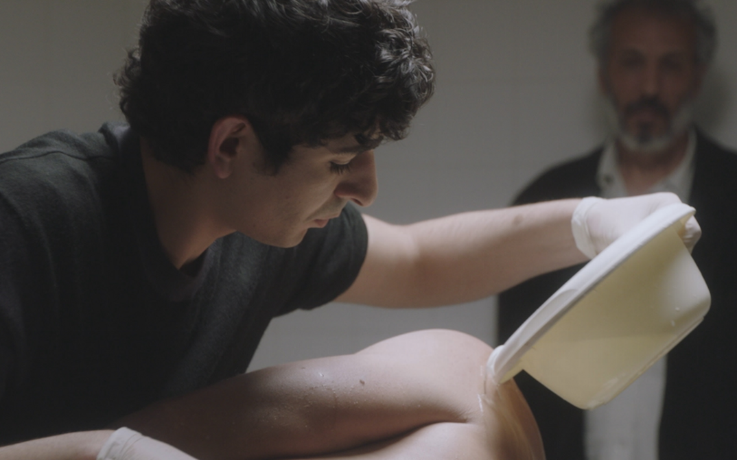 Film still from SIX FEET OVER: A young man washes a corpse.