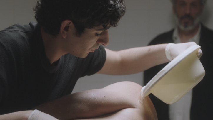 Filmstill aus SIX FEET OVER: Ein junger Mann wäscht eine nur angeschnitten sichtbare Leiche.