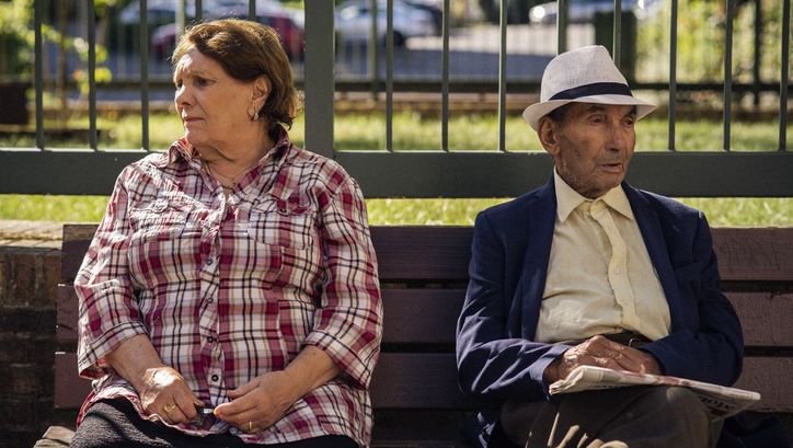 Filmstill aus THEIR ALGERIA. Ein älteres Paar sitzt auf einer Parkbank, sie blicken in entgegengesetzte Richtungen.