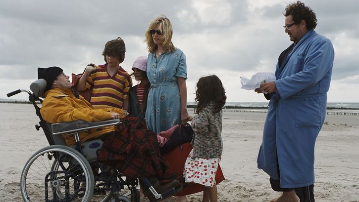 Filmstill aus LE SCAPHANDRE ET LE PAPILLON. Ein Mann im Rollstuhl ist am Strand umgeben von seiner Familie.