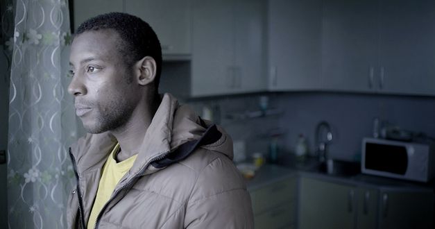 Still from the film „Llamadas desde Moscú“ by Luís Alejandro Yero. Close-up of a man standing in a kitchen wearing a jacket.