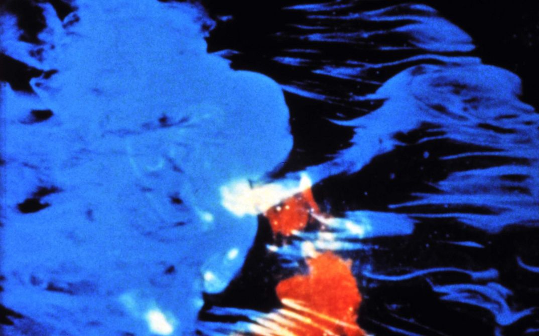 Film still from PASTORALE: Blue and red colour spots on a black background.