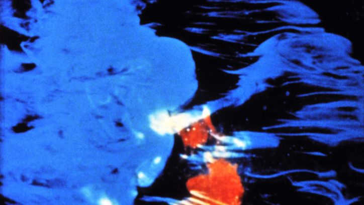 Film still from PASTORALE: Blue and red colour spots on a black background.