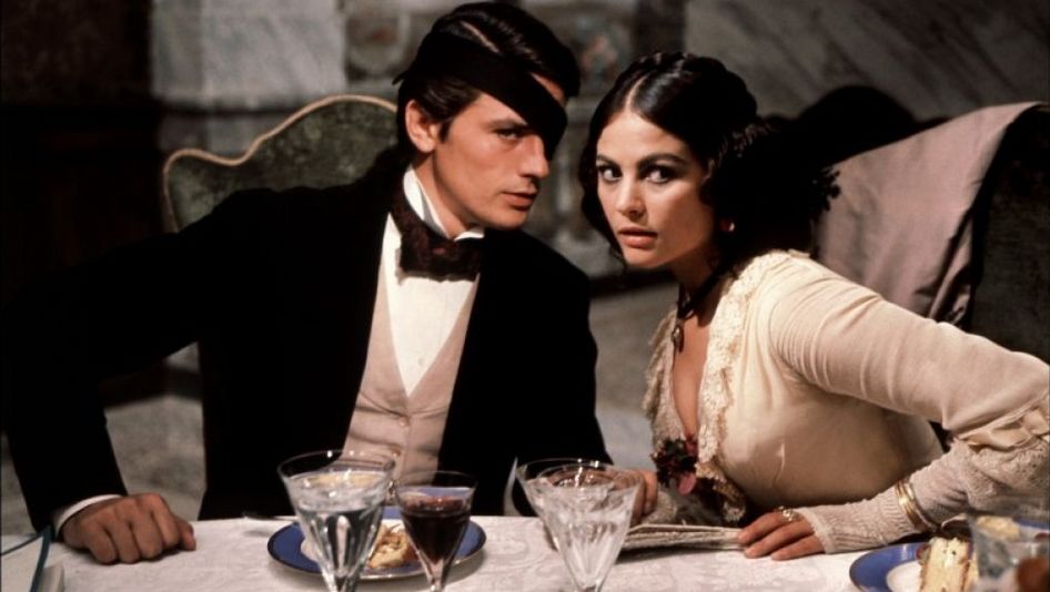 Film still from IL GATTOPARDO: An elegantly dressed couple sits at a festively laid table.
