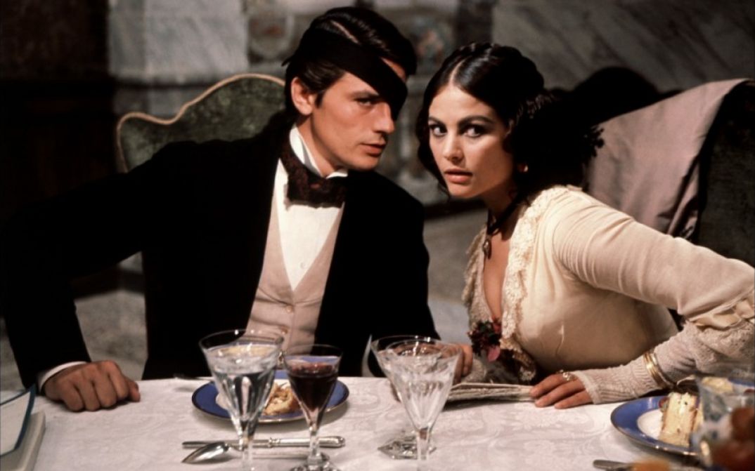 Film still from IL GATTOPARDO: An elegantly dressed couple sits at a festively laid table.