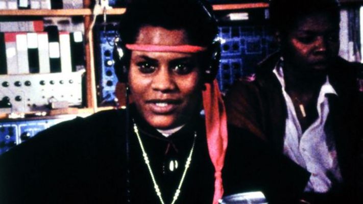 Film still from BORN IN FLAMES: Two women in a radio studio.