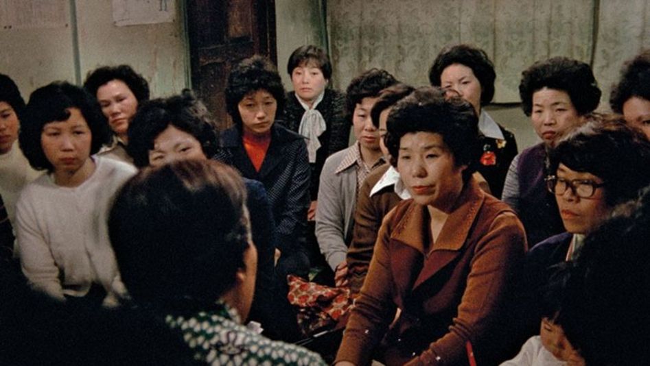 Film still from THE FAR ROAD: A group of women look at a person speaking.