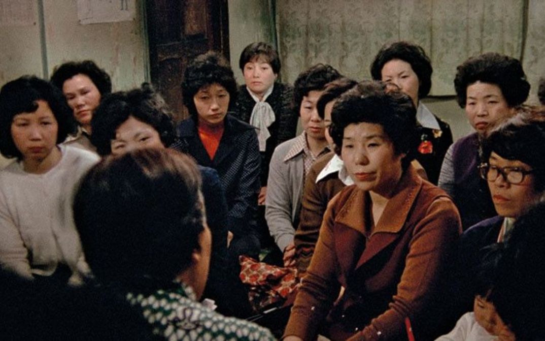Filmstill aus THE FAR ROAD: Eine Gruppe von Frauen blickt auf eine sprechende Person.