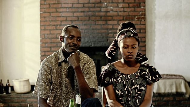 Filmstill from "The Bride" by. Myriam U. Birara. A woman looking down sadly is standing next to a man who is looking at her smiling.