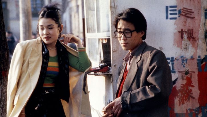 Filmstill aus XIAO WU: Ein Mann und einer Frau stehen an einer Straßenecke. Auf einer Hauswand sind chinesische Schriftzeichen zu sehen.