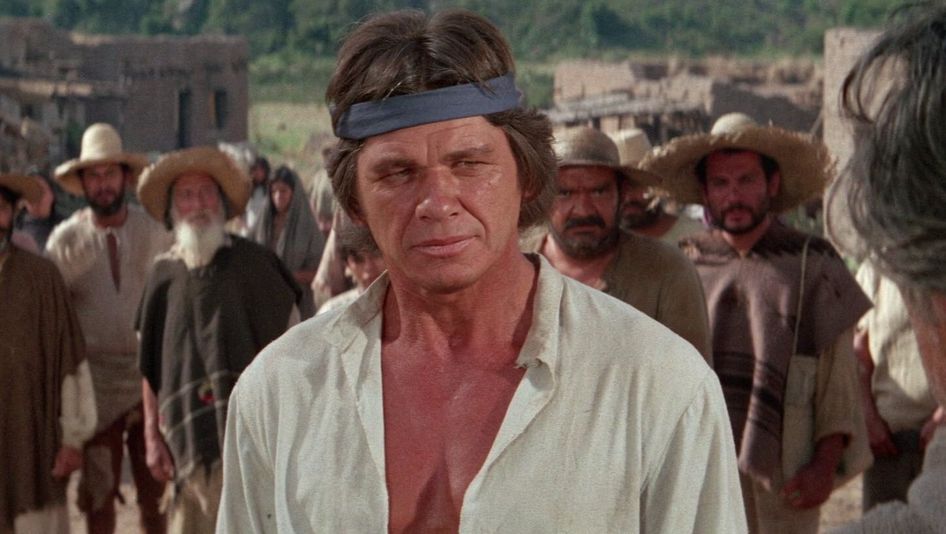 Film still from LA BATAILLE DE SAN SEBASTIAN: Charles Bronson in close-up, other men can be seen behind him.