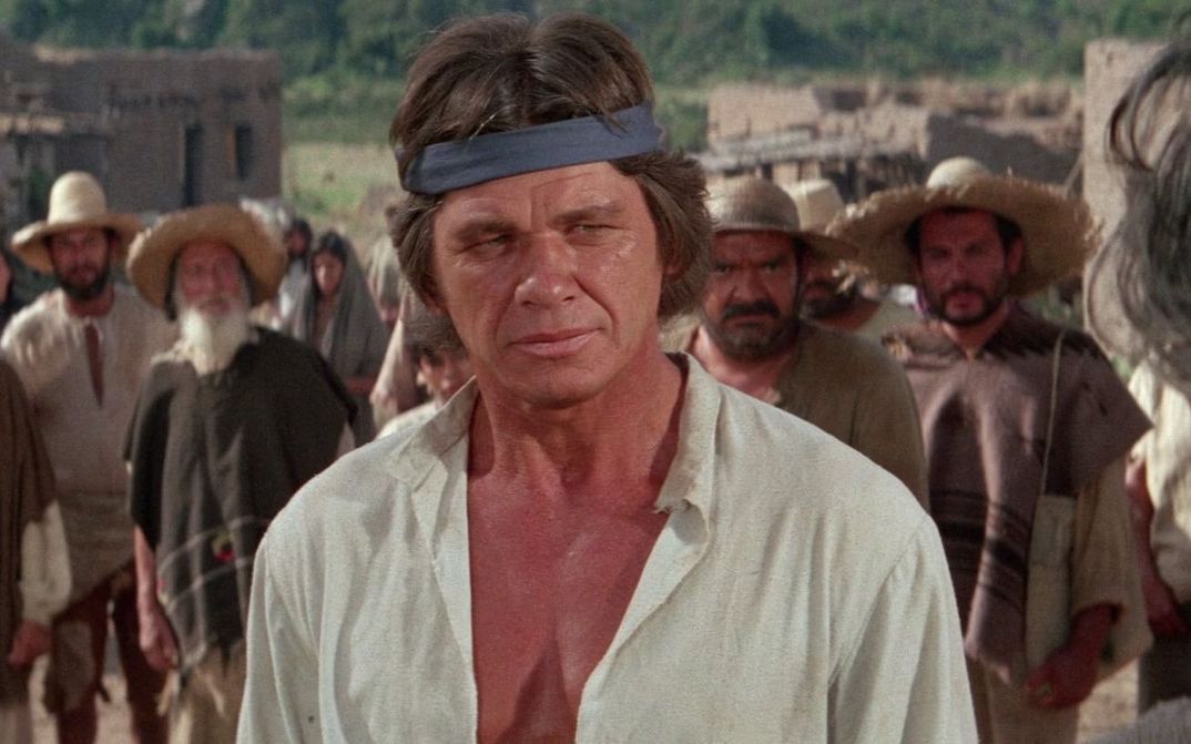 Film still from LA BATAILLE DE SAN SEBASTIAN: Charles Bronson in close-up, other men can be seen behind him.