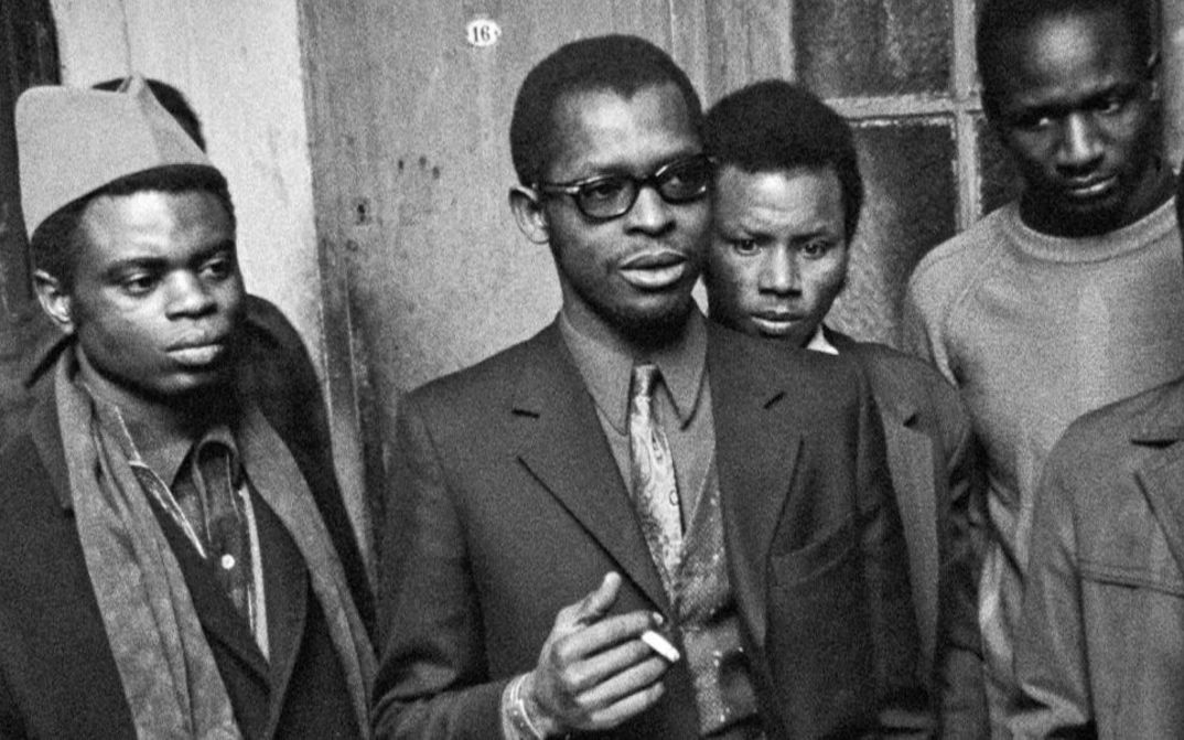 Film still from MES VOISINS: Four men, some in suits, scarves, headgear or glasses, or smoking.