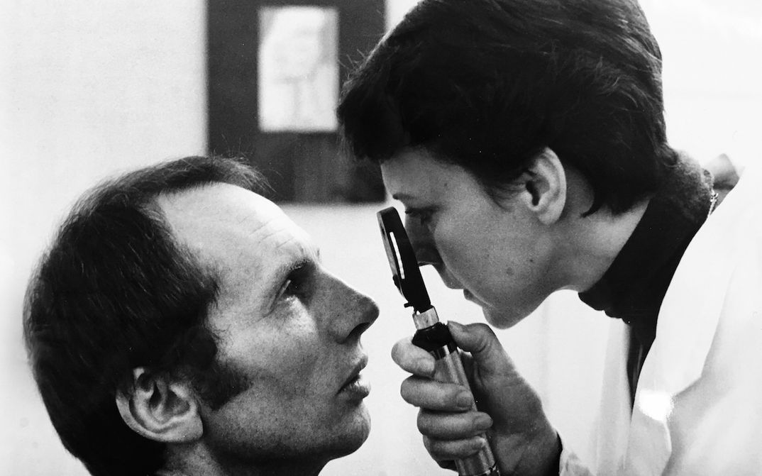 Filmstill aus ORDNUNG: Eine Augenärztin untersucht einen Patienten.