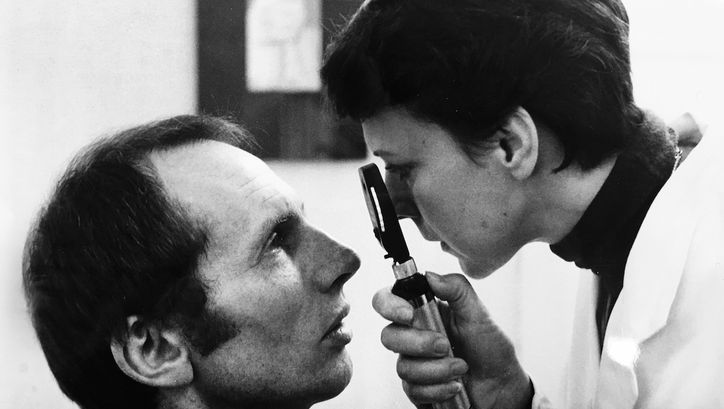 Film still from ORDNUNG: A female ophthalmologist examines a patient.
