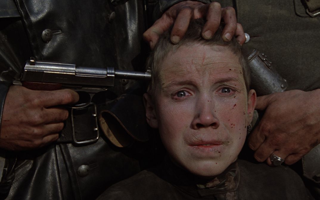 Filmstill aus IDI I SMOTRI: Man sieht das angstverzerrte Gesicht eines Jungen, an dessen Schläfe eine Pistole gehalten ist.