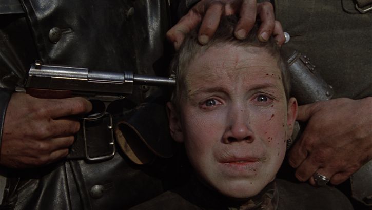 Filmstill aus IDI I SMOTRI: Man sieht das angstverzerrte Gesicht eines Jungen, an dessen Schläfe eine Pistole gehalten ist.