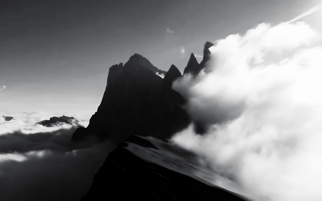 Filmstill aus LA NATURE: Die Silhouetten von Berggipfeln ragen aus einer Wolkendecke heraus. Links befindet sich eine große Wolke.